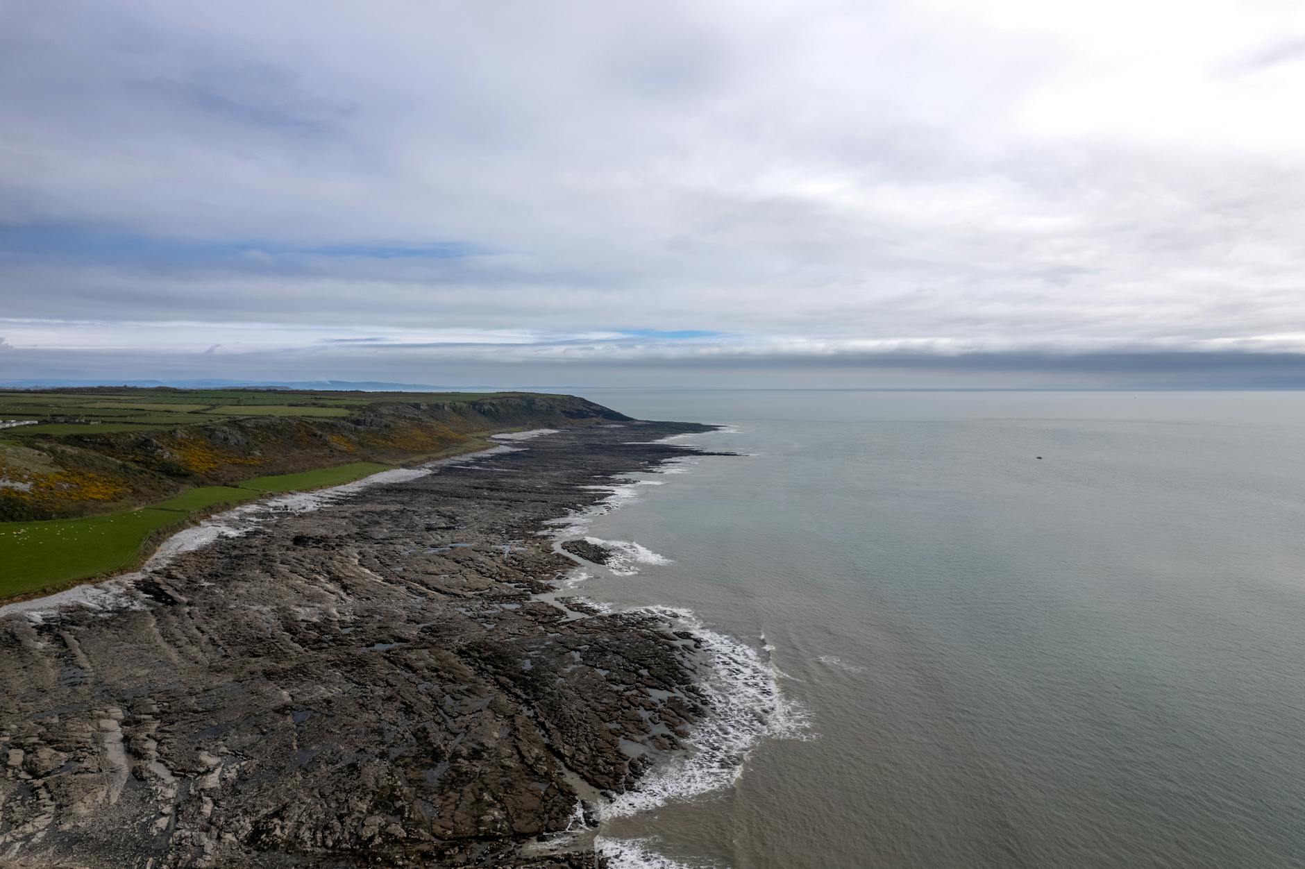 Klifowe wybrzeże Slade w Walii sfotografowane z drona pod chmurnym niebem