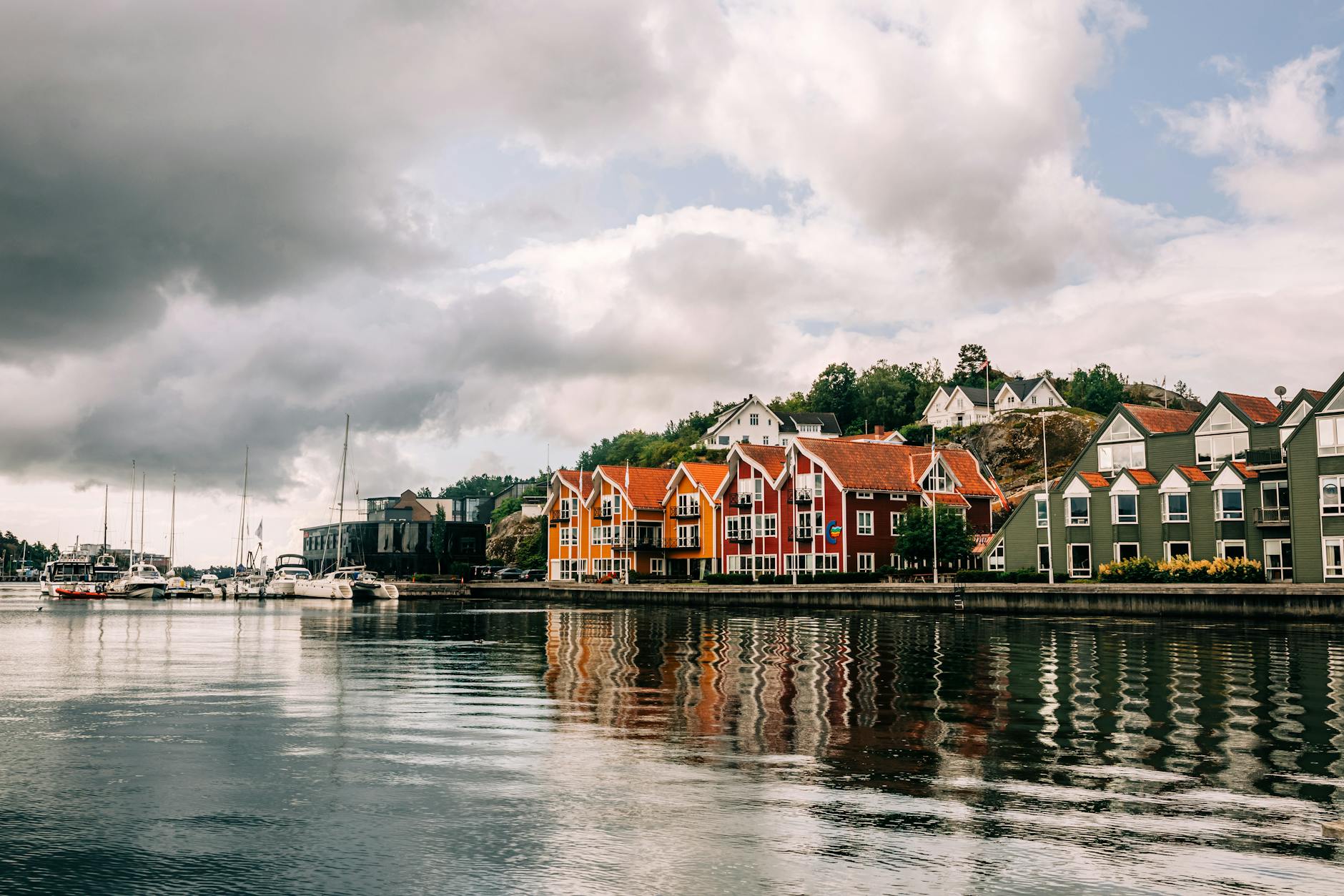 Kolorowe domy nad wodą w szwedzkim miasteczku pod dramatycznym niebem