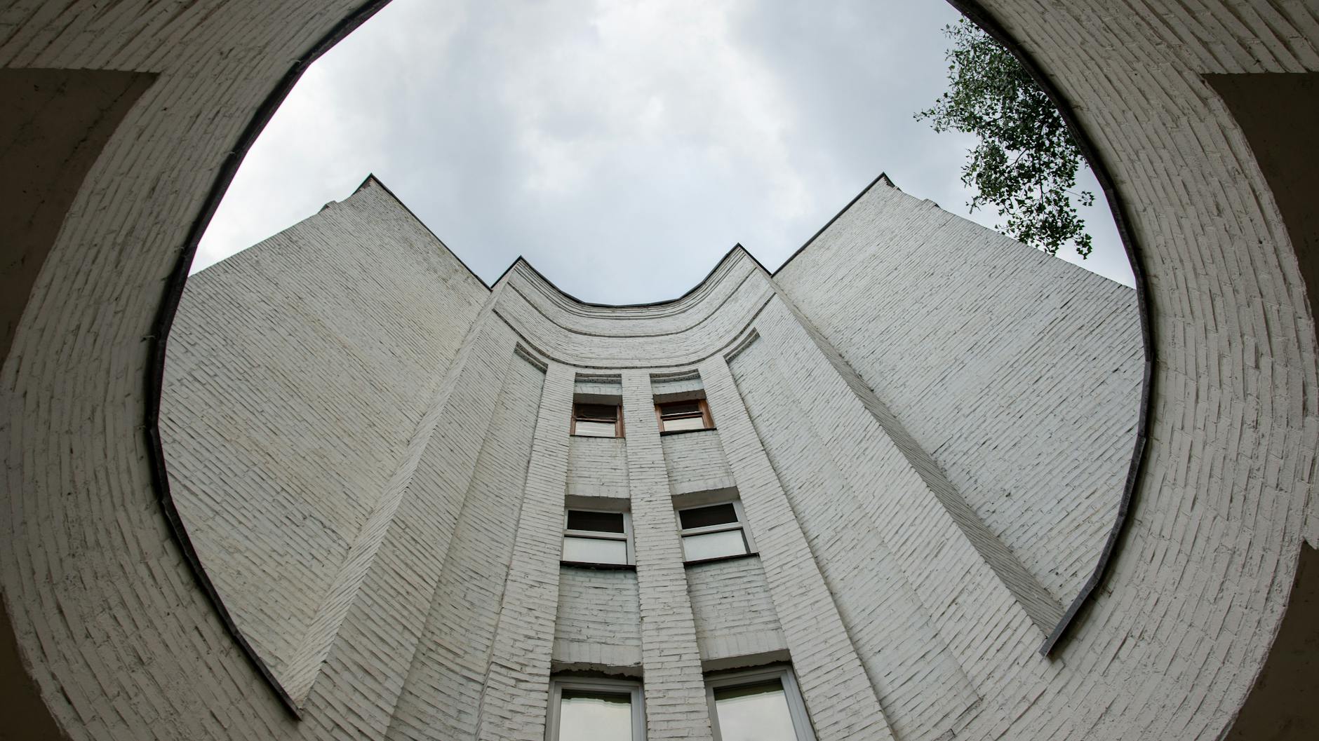 Modernistyczny biały budynek z zakrzywionej cegły sfotografowany z dołu