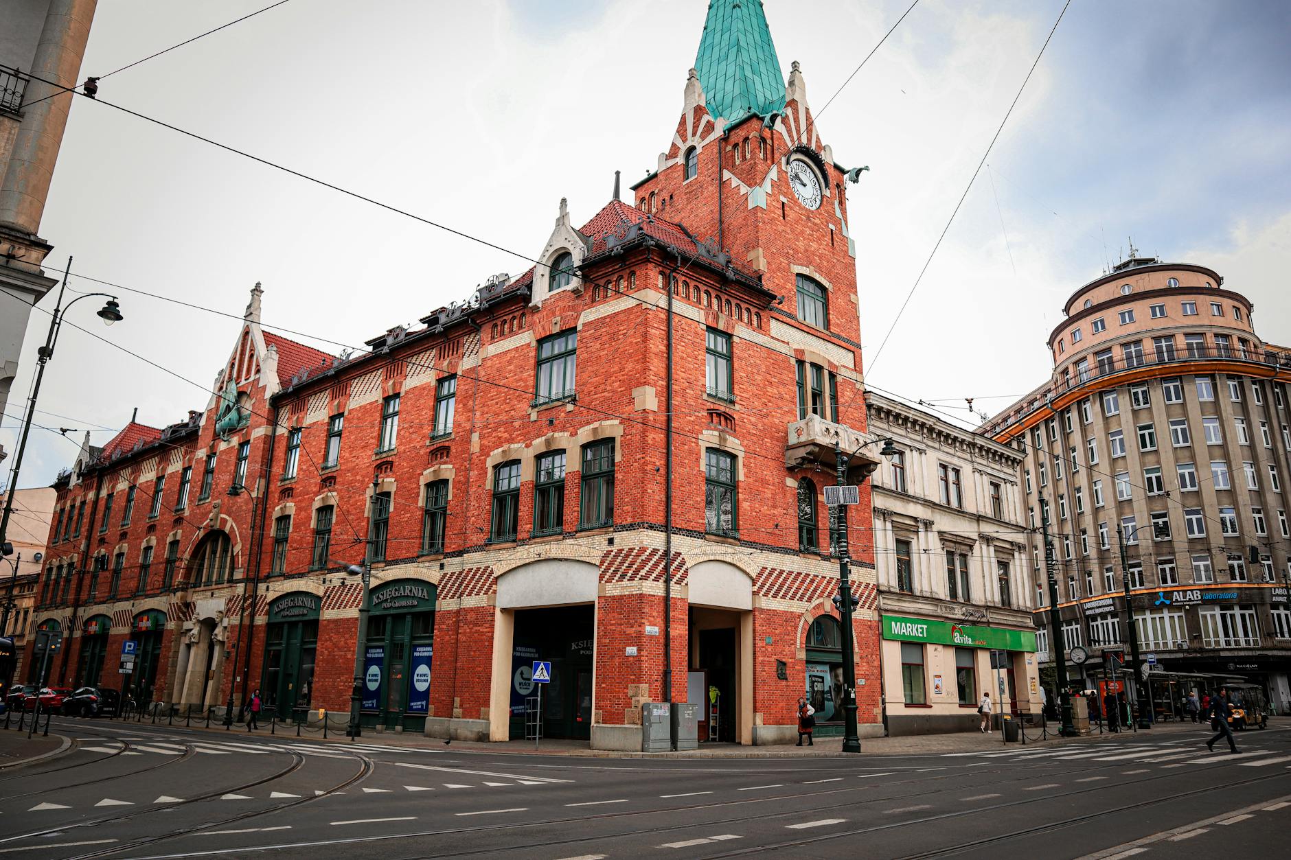 Modernistyczny narożny budynek z czerwonej cegły i wieżą zegarową w Krakowie