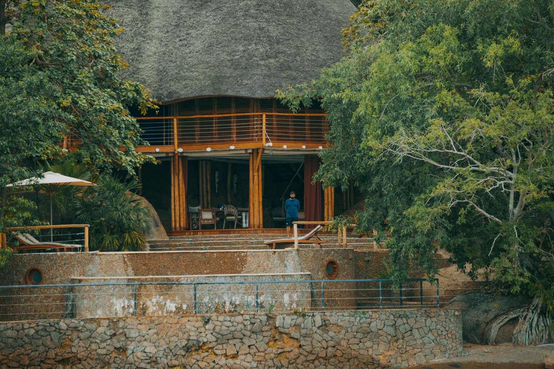 Rustyczny eco-lodge nad jeziorem wśród zieleni z osobą przy wejściu