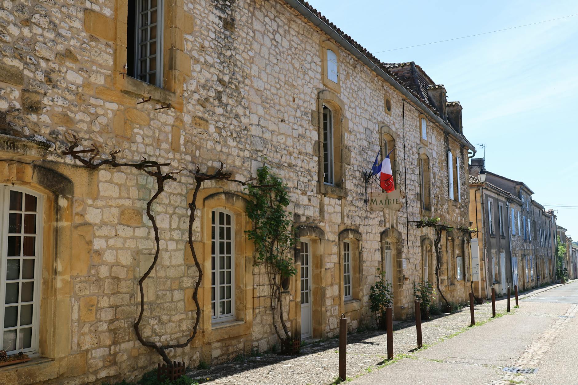 Zabytkowa uliczka francuskiego miasteczka z kamiennymi domami i flagami