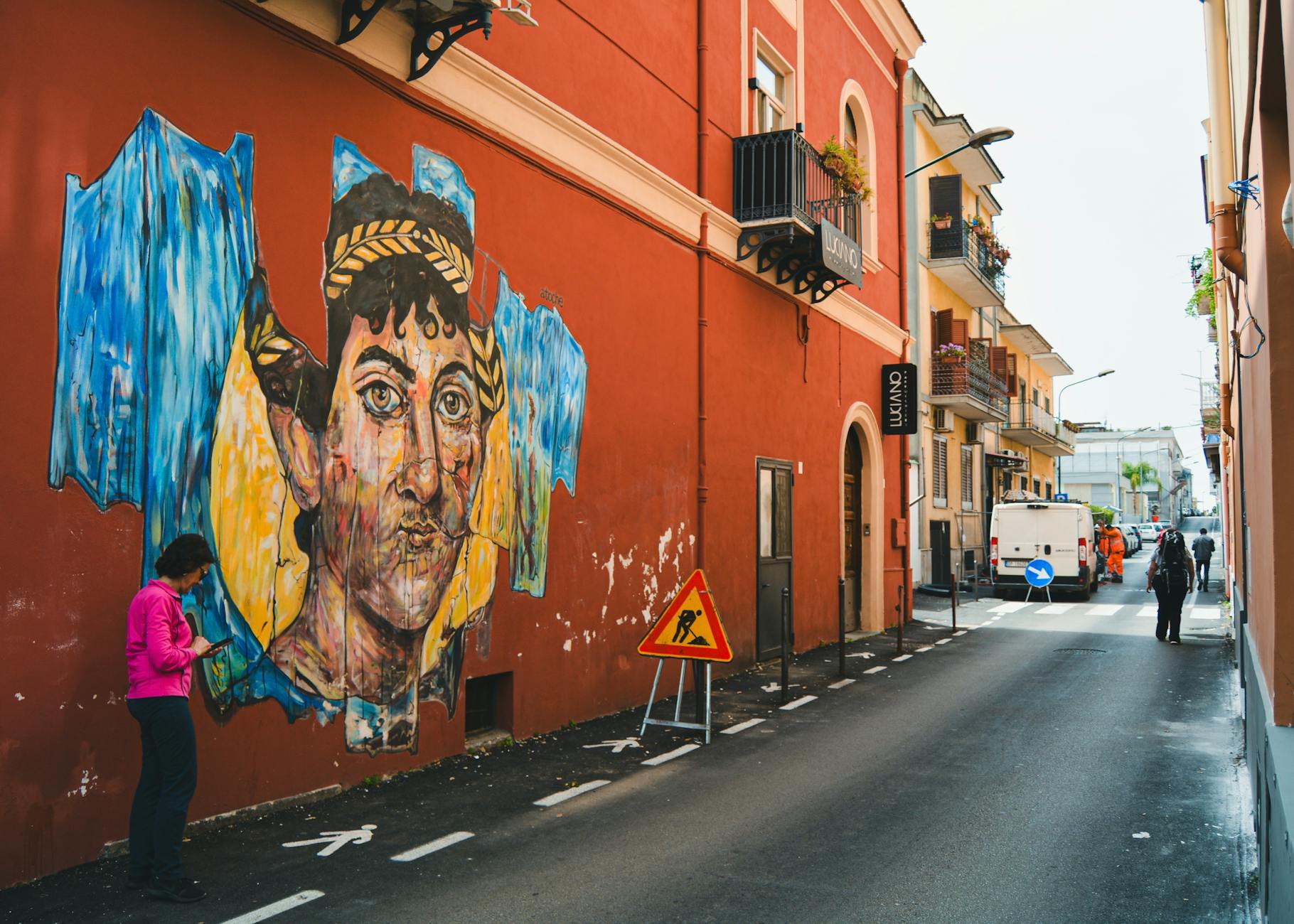 Kolorowy mural na czerwonej kamienicy w wąskiej włoskiej uliczce