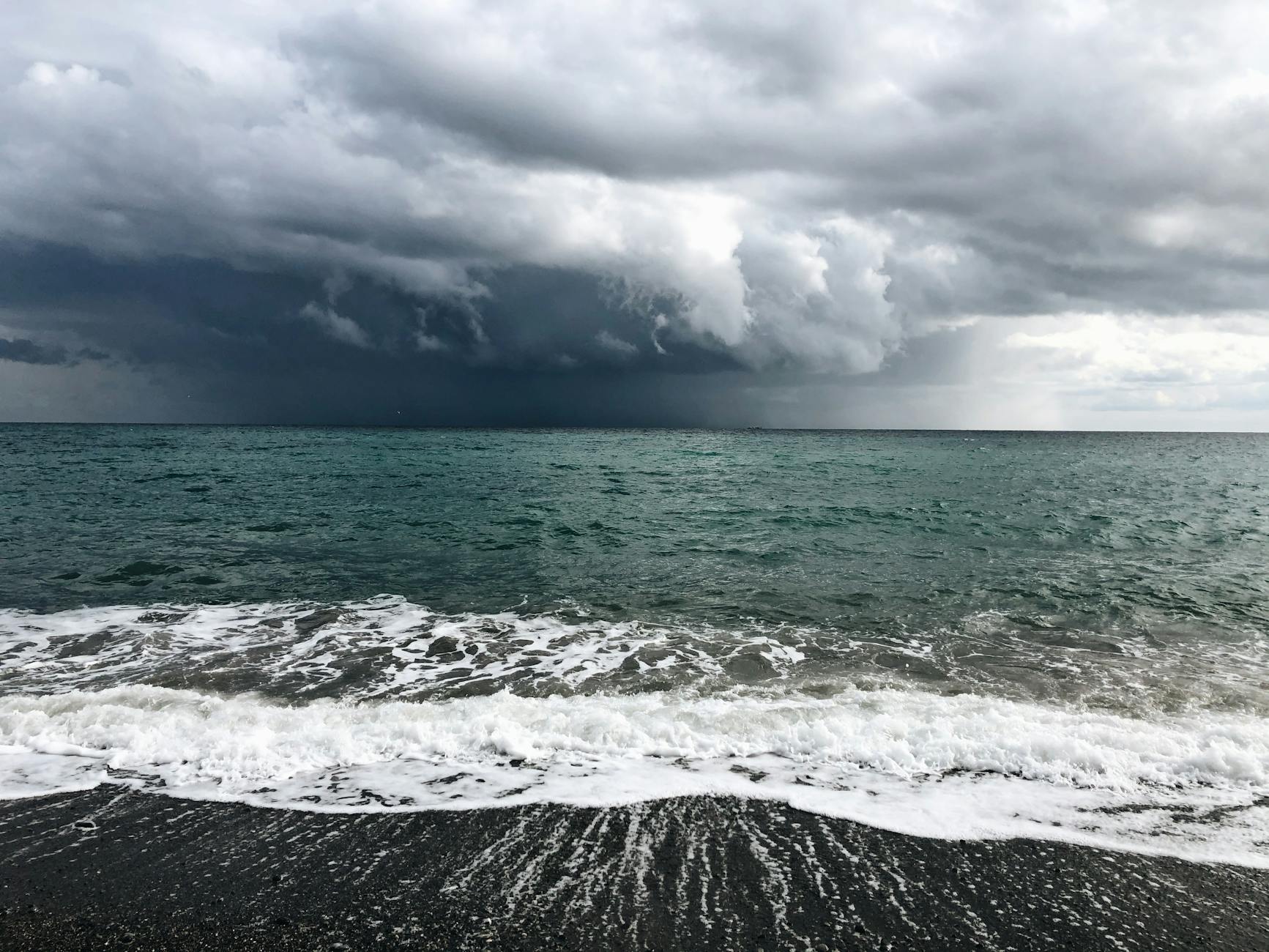 Burzowe chmury nad wzburzonym Morzem Czarnym i ciemną piaszczystą plażą