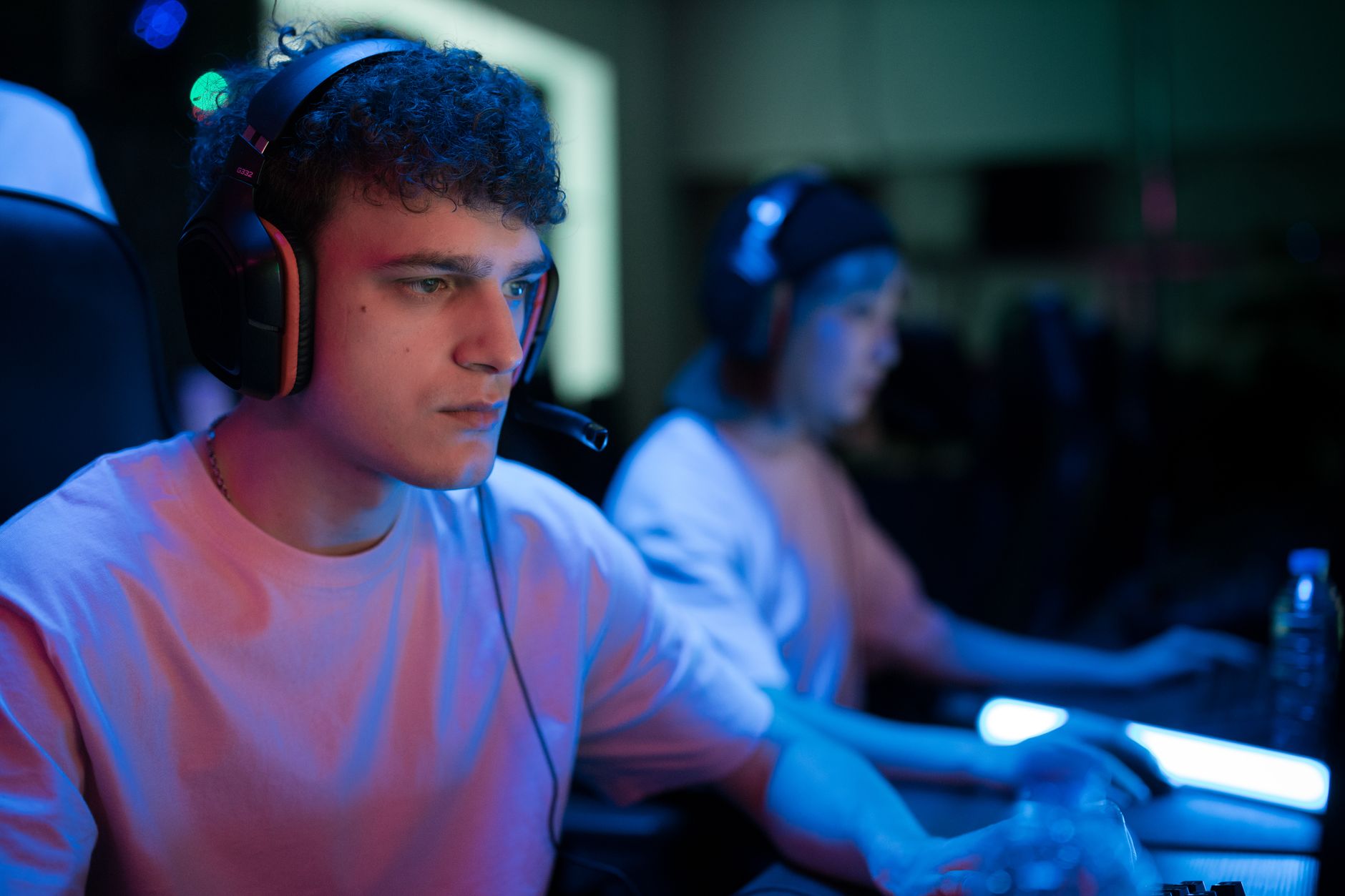 Gracz e-sportowy w słuchawkach przy komputerze w neonowym oświetleniu