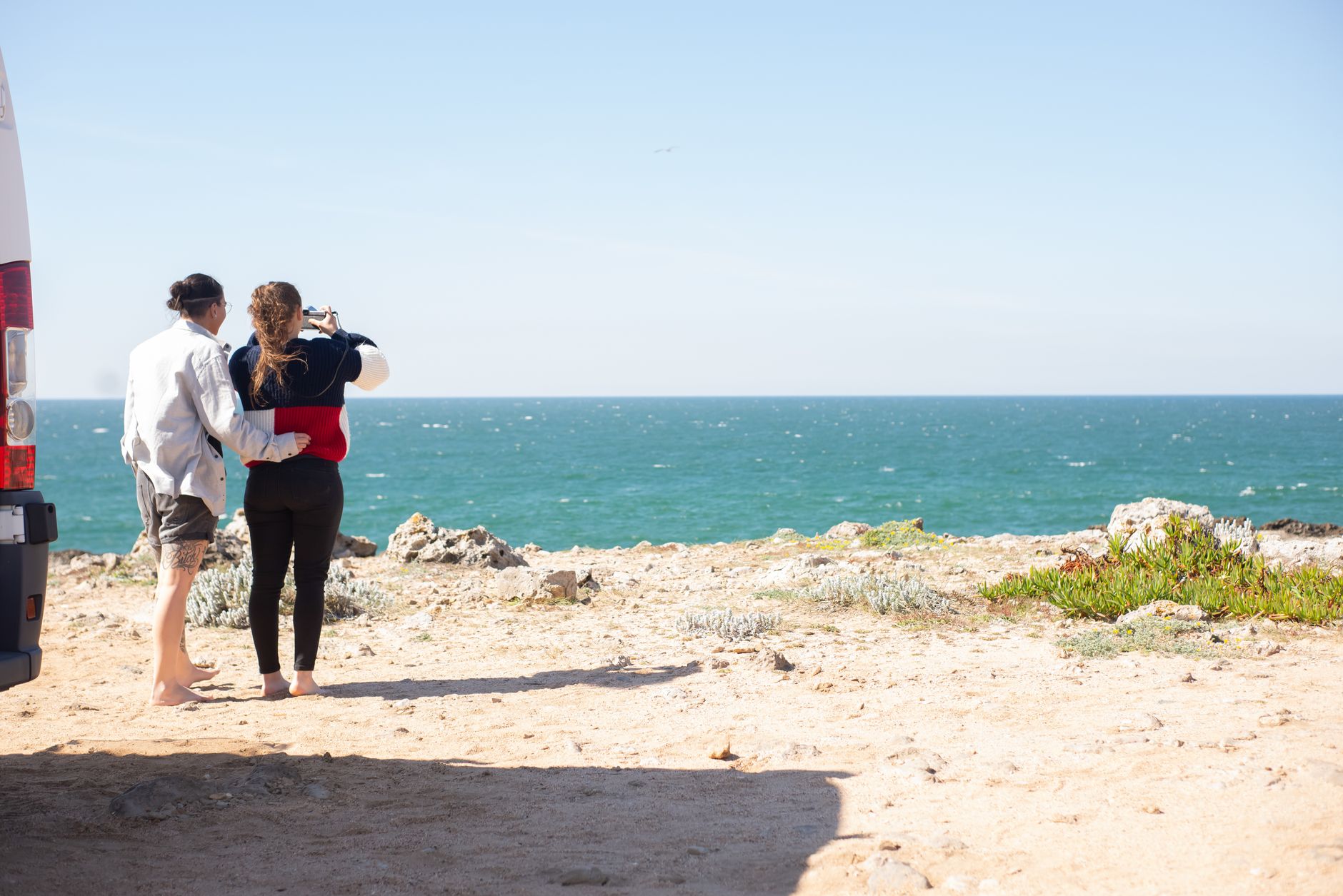 Para przy kamperze fotografuje ocean podczas słonecznego dnia w Portugalii